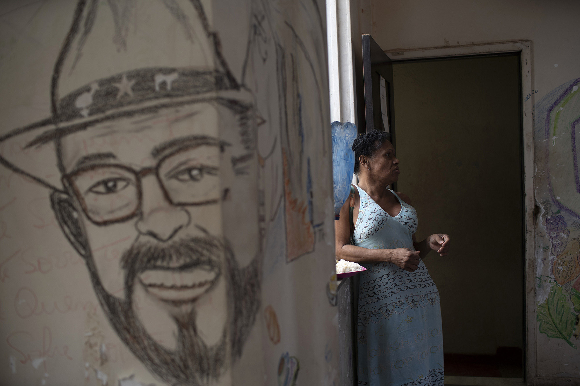 Claudinha is a resident of Casa Nem, a squat occupied by members of the LGBTQ community who are in self-quarantine as a protective measure against the new coronavirus, in Rio de Janeiro, Brazil, Wednesday, July 8, 2020. Claudinha is standing around the corner from a mural depicting Joao W. Nery, recognized as the first transgender man to have undergone sex-change surgery in Brazil.