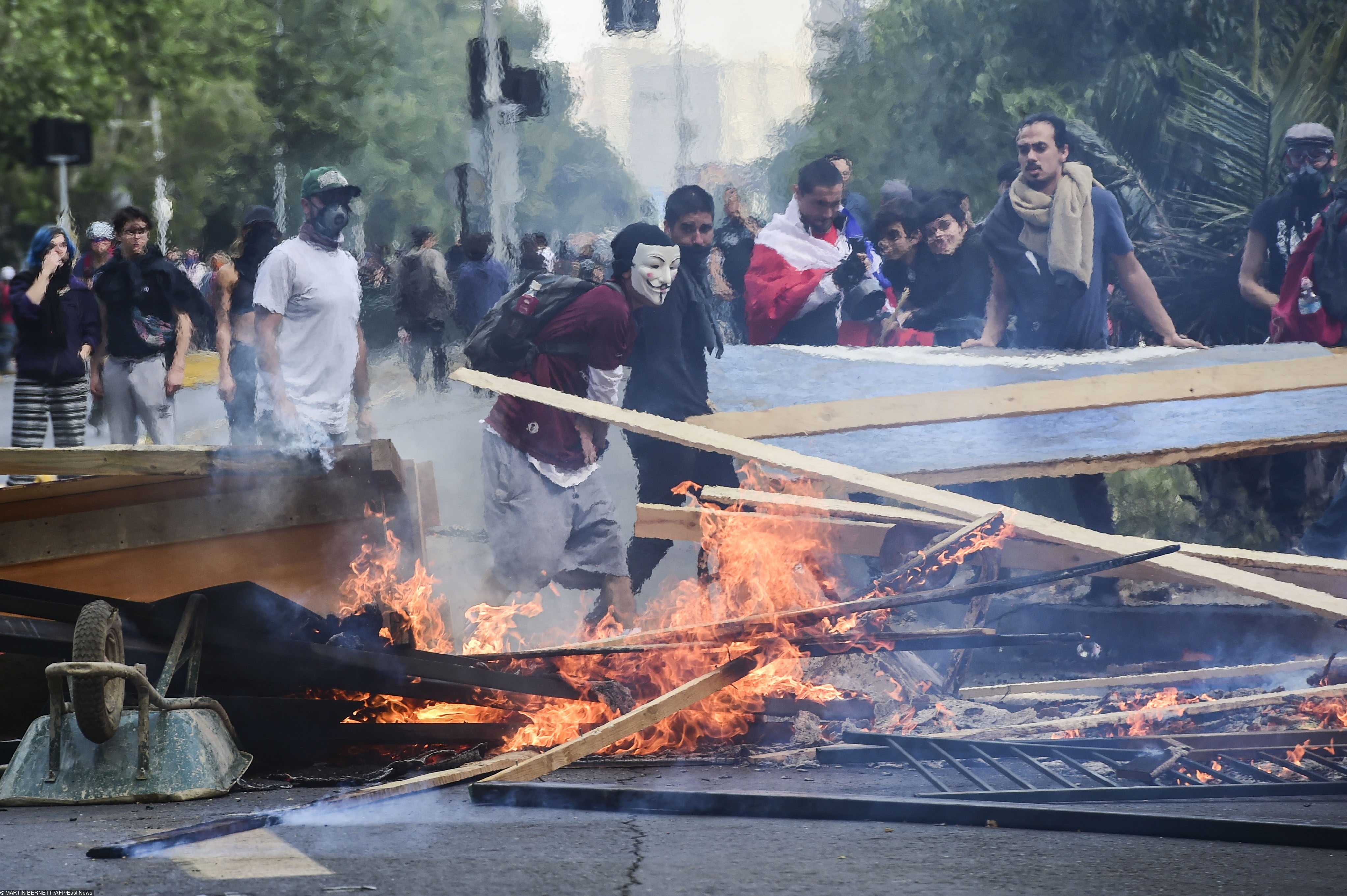Демонстранты в Сантьяго возводят баррикады Demonstrators set up barricades during clashes between protesters and the riot police in Santiago, on October 19, 2019. - Chile's president declared a state of emergency in Santiago Friday night and gave the military responsibility for security after a day of violent protests over an increase in the price of metro tickets. (Photo by Martin BERNETTI / AFP)
