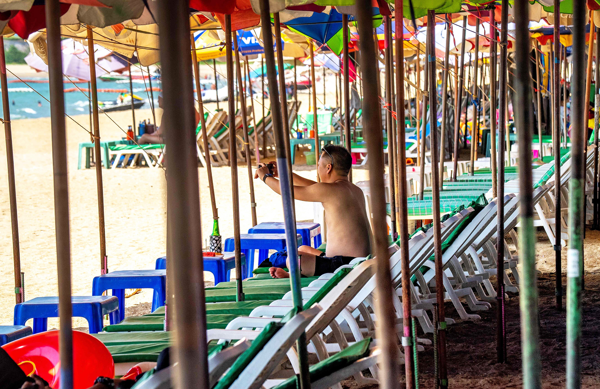 Малолюдный пляж в Паттайе, 7 марта A tourist takes photos as he sits on sun loungers on an empty beach in Pattaya on March 7, 2020, as visitor numbers in the region have plunged due to the outbreak of the COVID-19 coronavirus. (Photo by Mladen ANTONOV / AFP)