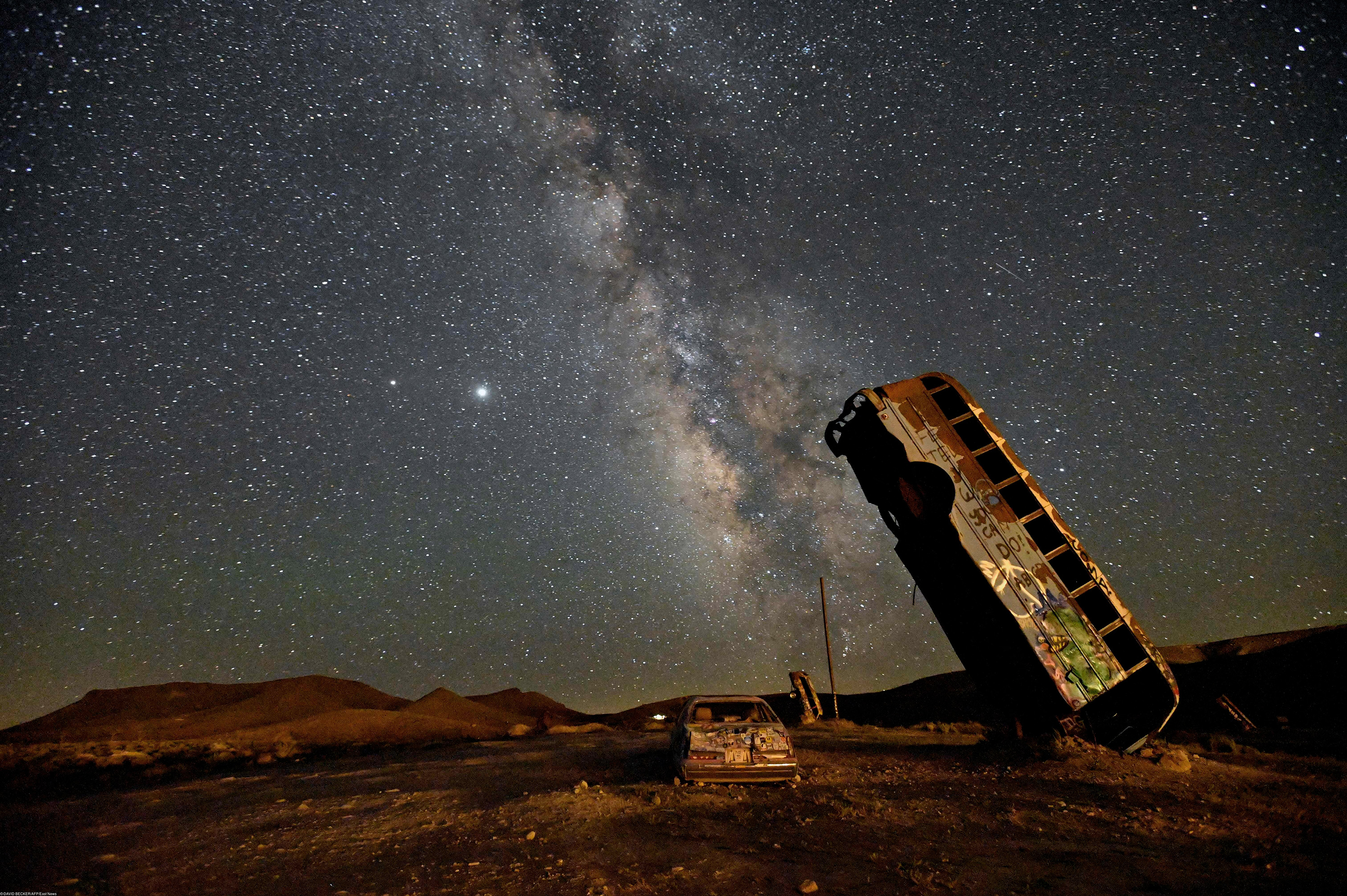 Вид на Млечный Путь с территории The Milky Way galaxy is seen in the sky above the International Car Forest of the Last Church in Goldfield, Nevada on July 18, 2020. - The roadside attraction, created in 2002 by Mark Rippie, has over 36 automobiles including cars, trucks, vans and buses that have been balanced on their ends or stacked on top one of another. (Photo by David Becker / AFP)
