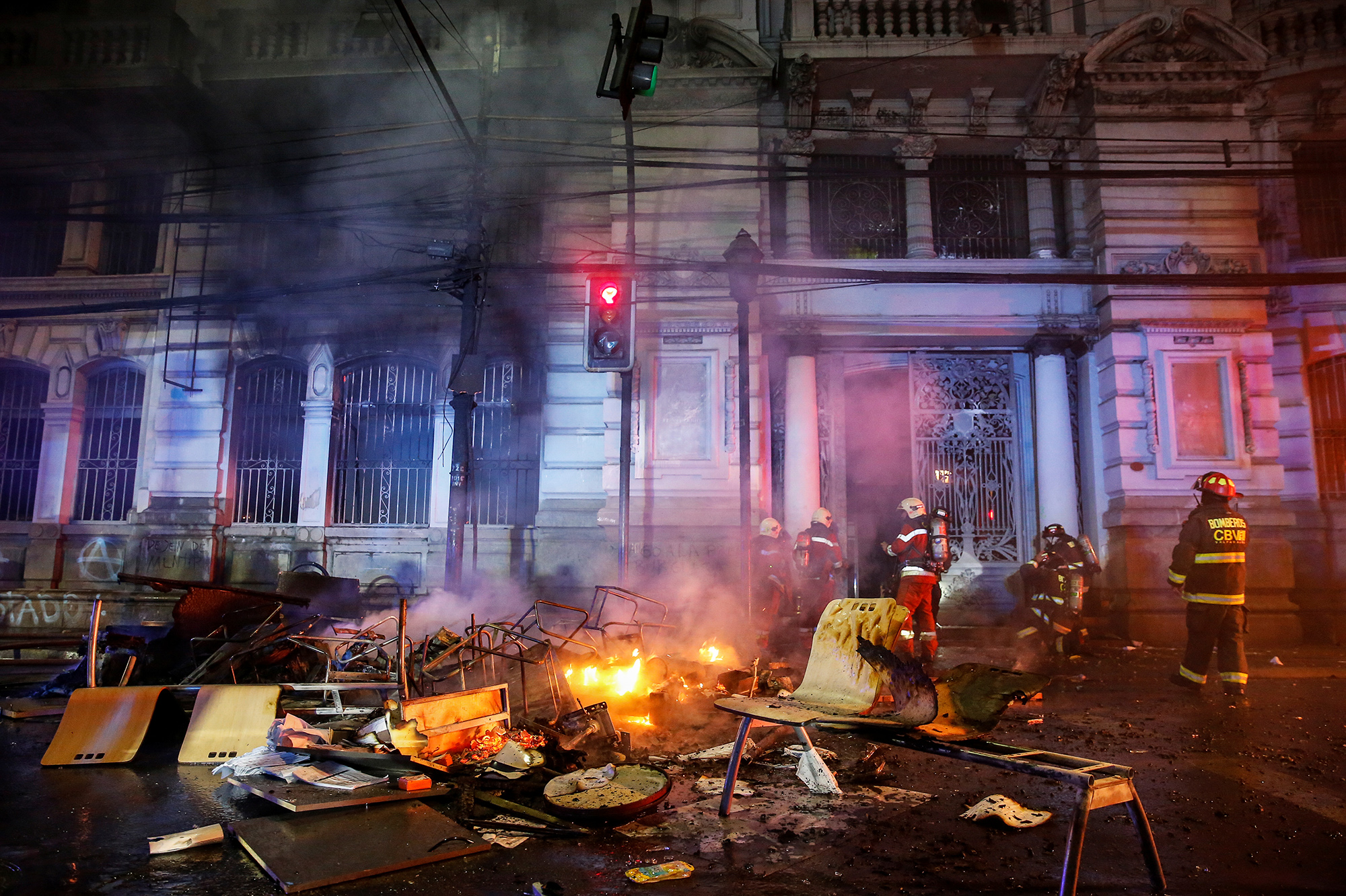 Последствия поджогов в Вальпараисо Firemen work near burnt furniture and objects outside the building of Chilean newspaper El Mercurio de Valparaiso during a protest against the government in Valparaiso, Chile