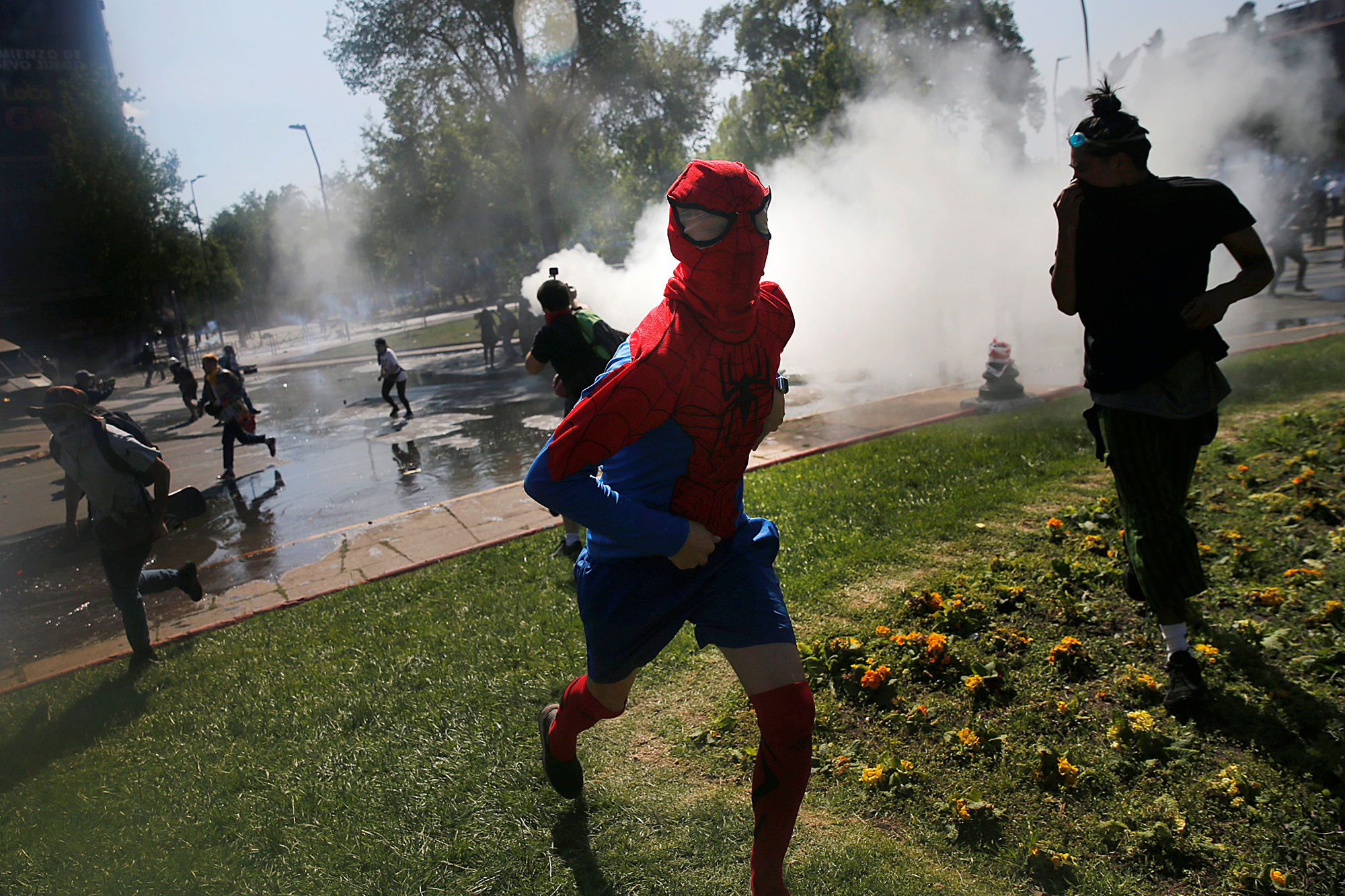Полиция применяет слезоточивый газ для разгона демонстрантов A demonstrator dressed as Spiderman runs from tear gas during a protest against Chile's state economic model in Santiago October 20, 2019.