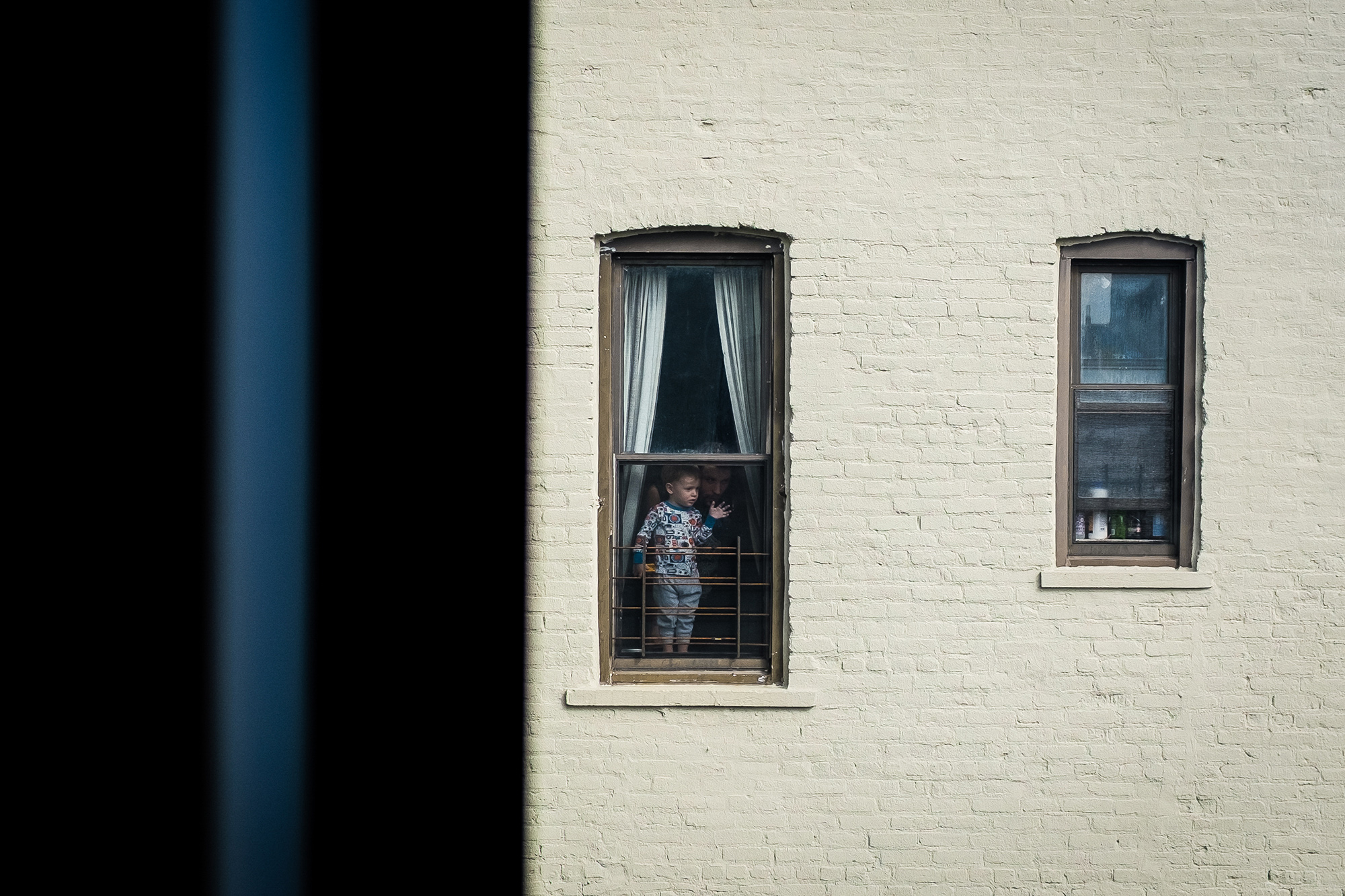 Юный житель Бруклина на карантине A little boy and his father can be seen looking out of a window in Brooklyn, New York, USA, 16 March 2020. New York City Public schools will close due to coronavirus until at least 20 April. EPA-EFE/Alba Vigaray
