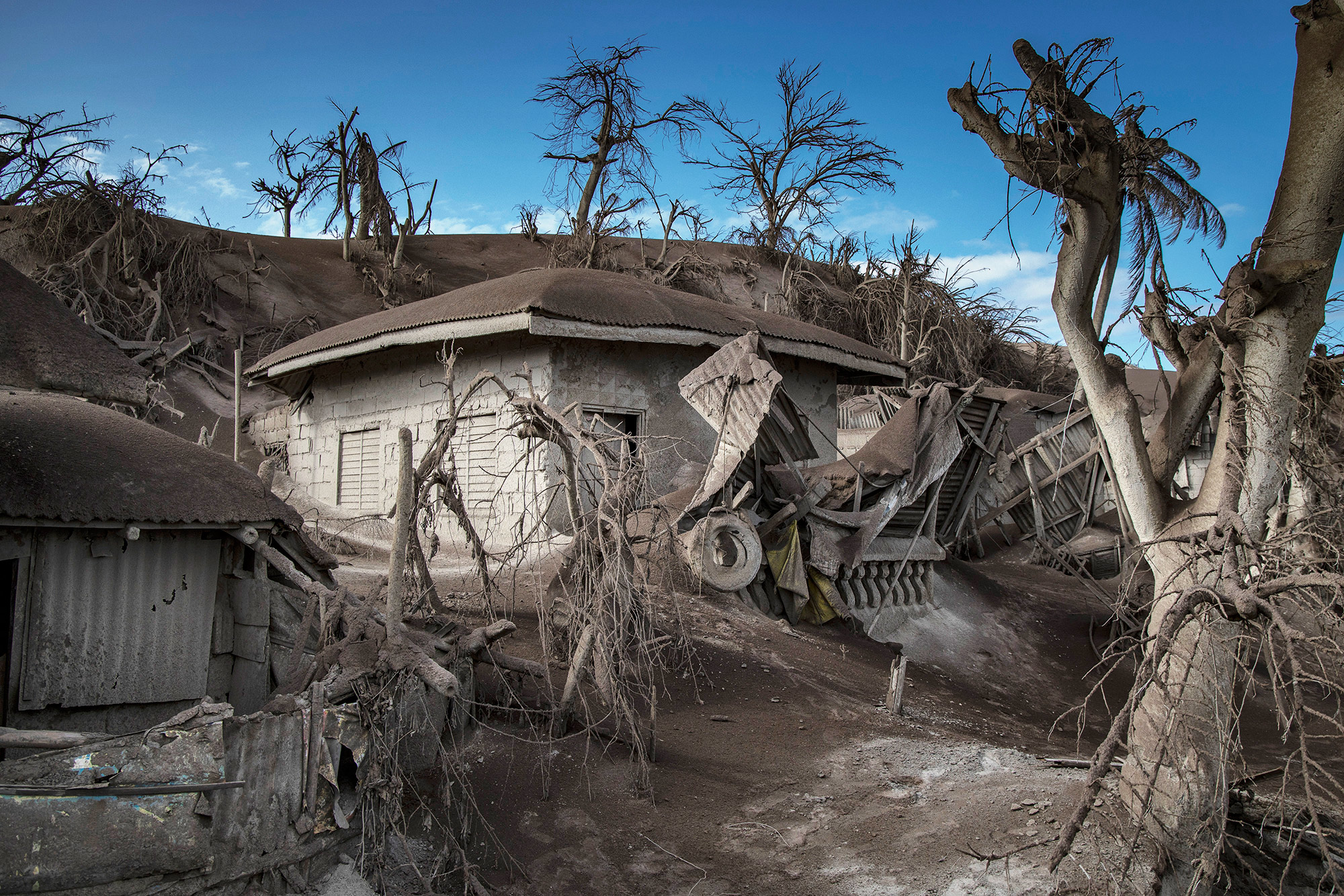 TAAL VOLCANO ISLAND, PHILIPPINES - JANUARY 14: Houses near Taal Volcano's crater is seen buried in volcanic ash from the volcano's eruption on January 14, 2020 in Taal Volcano Island, Batangas province, Philippines. The Philippine Institute of Volcanology and Seismology raised the alert level to four out of five, warning that a hazardous eruption could take place anytime, as authorities have evacuated tens of thousands of people from the area. An estimated $10 million worth of crops and livestock have been damaged by the on-going eruption, according to the country's agriculture department. (Photo by Ezra Acayan/Getty Images)