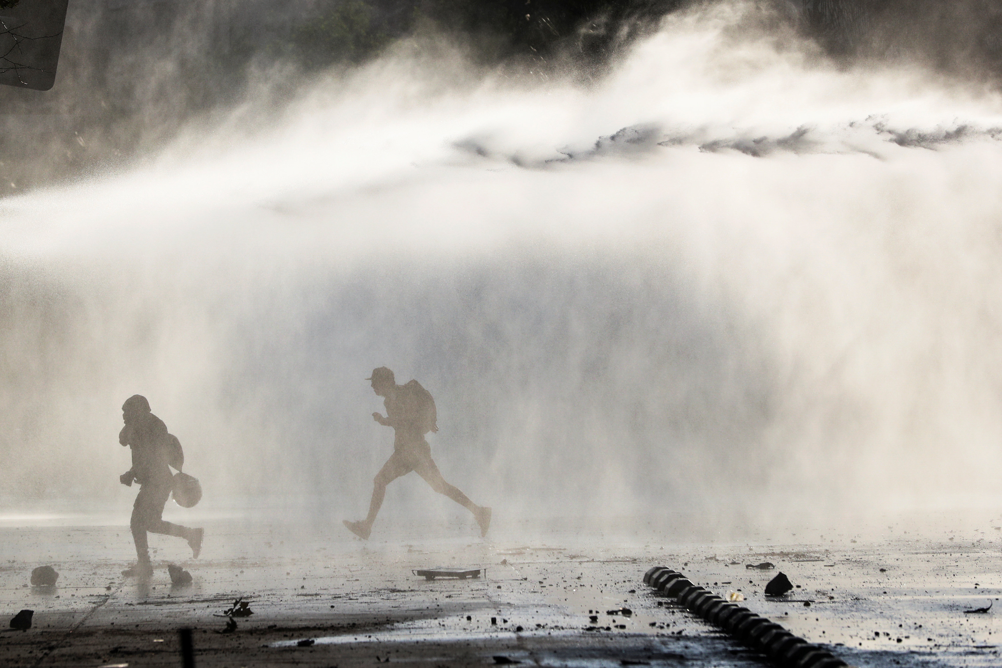 Полиция также активно применяет водометы DATE IMPORRTED:October 19, 2019Demonstrators run from the police water cannon during a protest against the increase in subway ticket prices in Santiago, Chile, October 19, 2019
