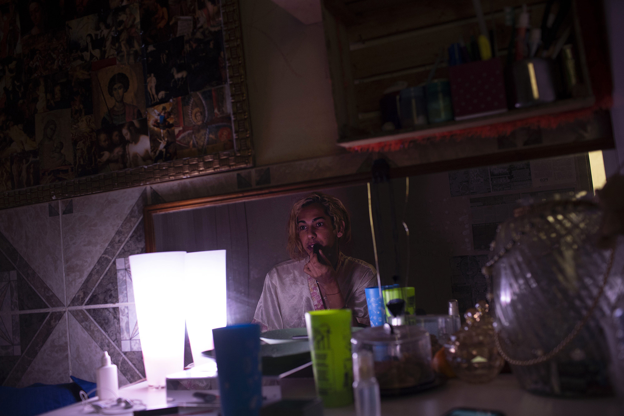 Transgender Alex looks into mirror as she puts on lipstick, in her room at the squat known as Casa Nem in Rio de Janeiro, Brazil, Wednesday, July 8, 2020. The six-floor building is home to members of the LGBTQ community riding out the pandemic behind closed doors.
